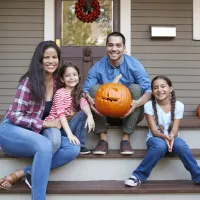 family sitting on front porch with pumpkins