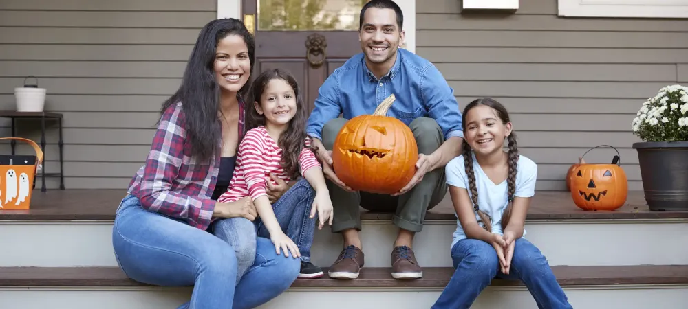 family sitting on front porch with pumpkins