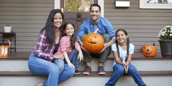 family sitting on front porch with pumpkins