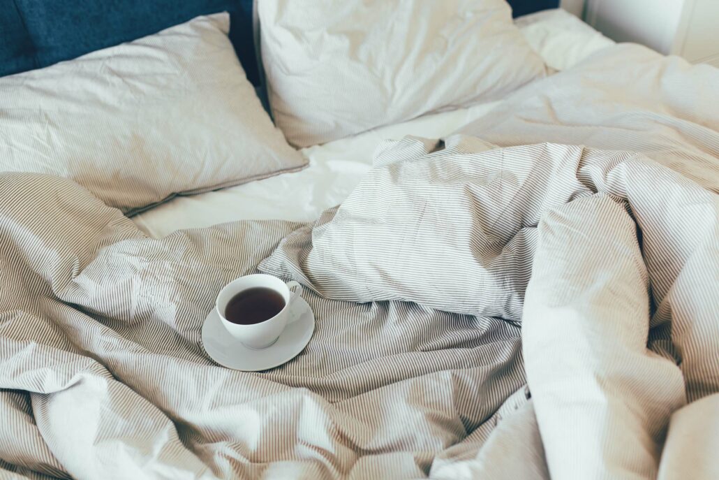 Bed not made With Clean White Pillows And Bed Sheets with coffee in the bed